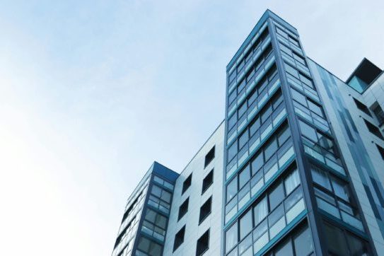 Low-angle view of a modern glass skyscraper against a clear sky in Poole, UK.